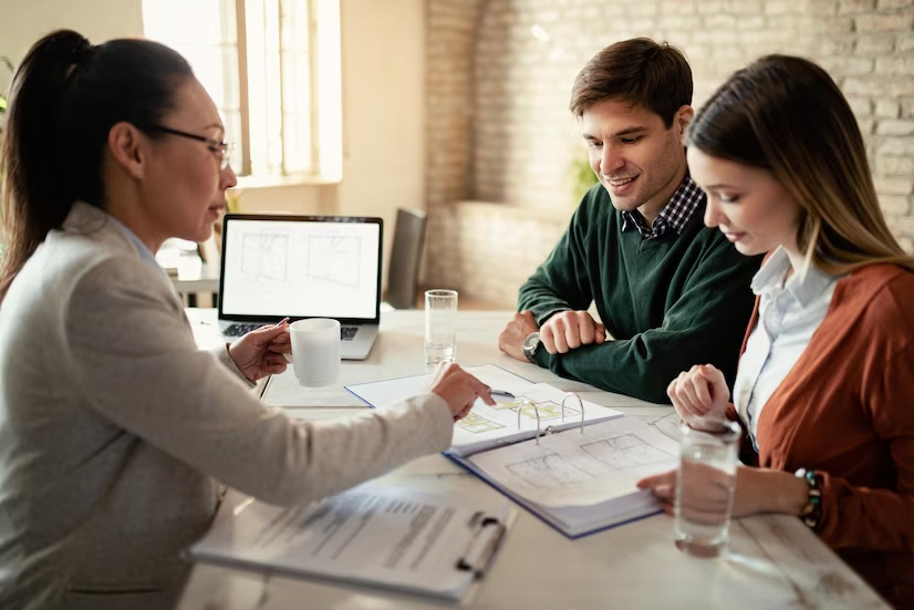 Insurance advisor reviewing coverage paperwork with a couple during an in-person meeting